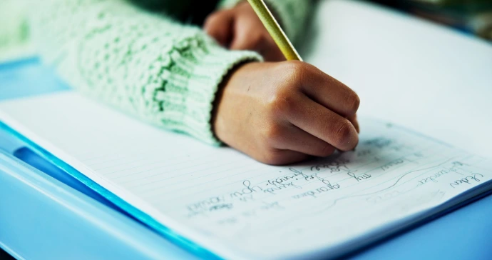 close up of child writing in a notebook 