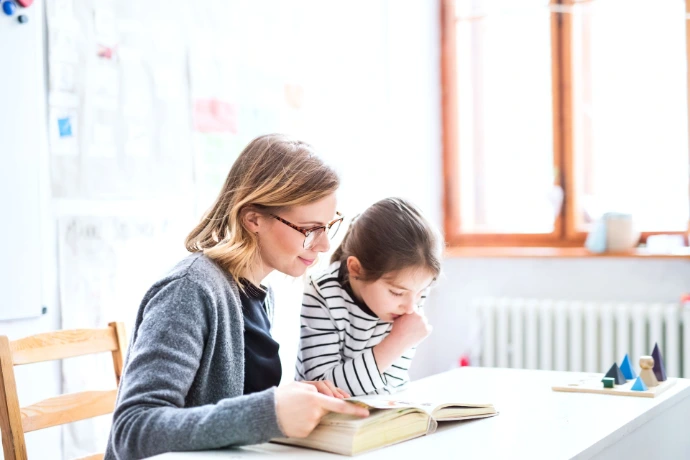 A teacher teaching a child how to read a book 